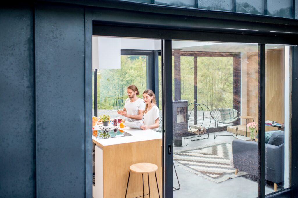 Ett par framför sitt moderna hus som njuter av ett bra inomhusklimat med frånluftsvärmepump